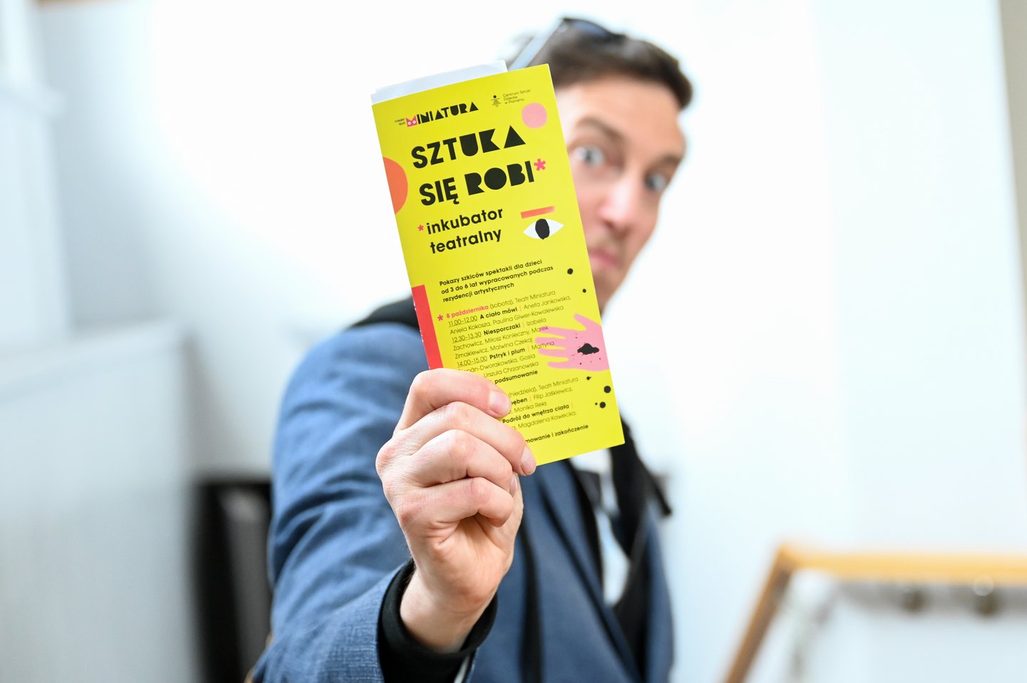 Mężczyzna trzyma przed sobą ulotkę z napisem: Sztuka się robi.