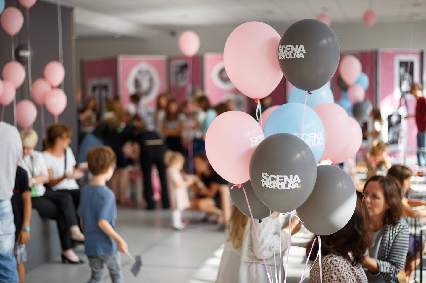 W oszklonym foyer Sceny Wspólnej znajdują się dorośli oraz dzieci. Dookoła ludzi kolorowe balony z napisem: Scena Wspólna.