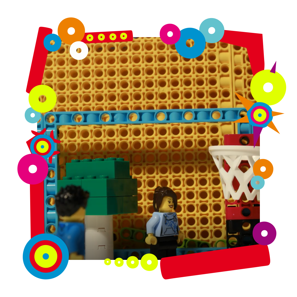 Na zdjęciu budowla stworzona z klocków Lego. Obok budowli stoją dwa ludziki. Dookoła zdjęcia kolorowa ramka.