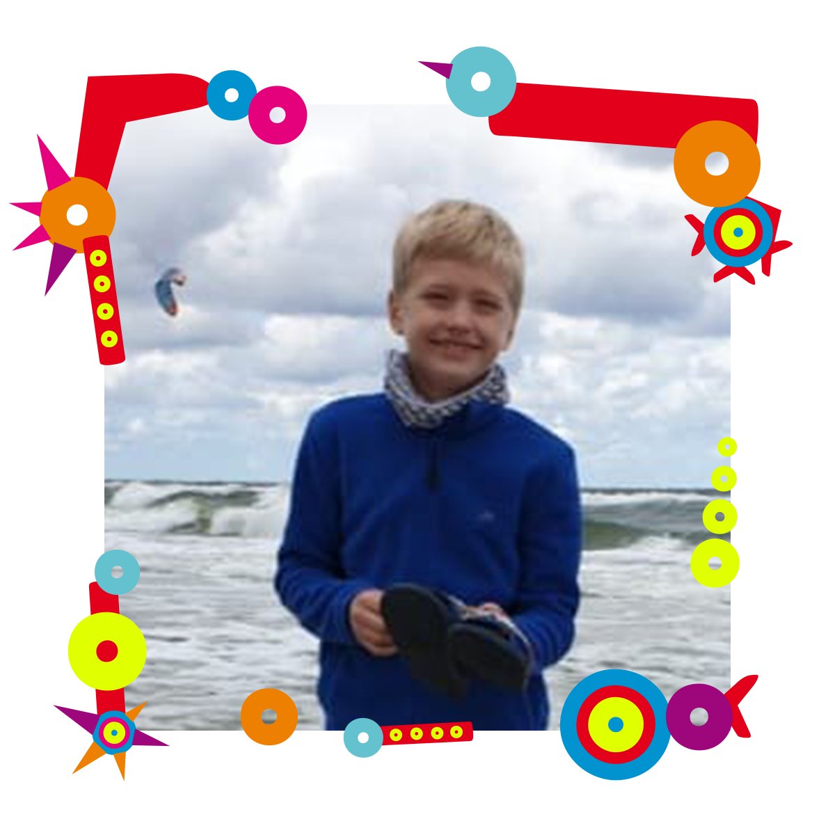 Na zdjęciu uśmiechnięty chłopiec. Stoi na tle morza. W dłoniach trzyma klapki. Dookoła zdjęcia kolorowa ramka.