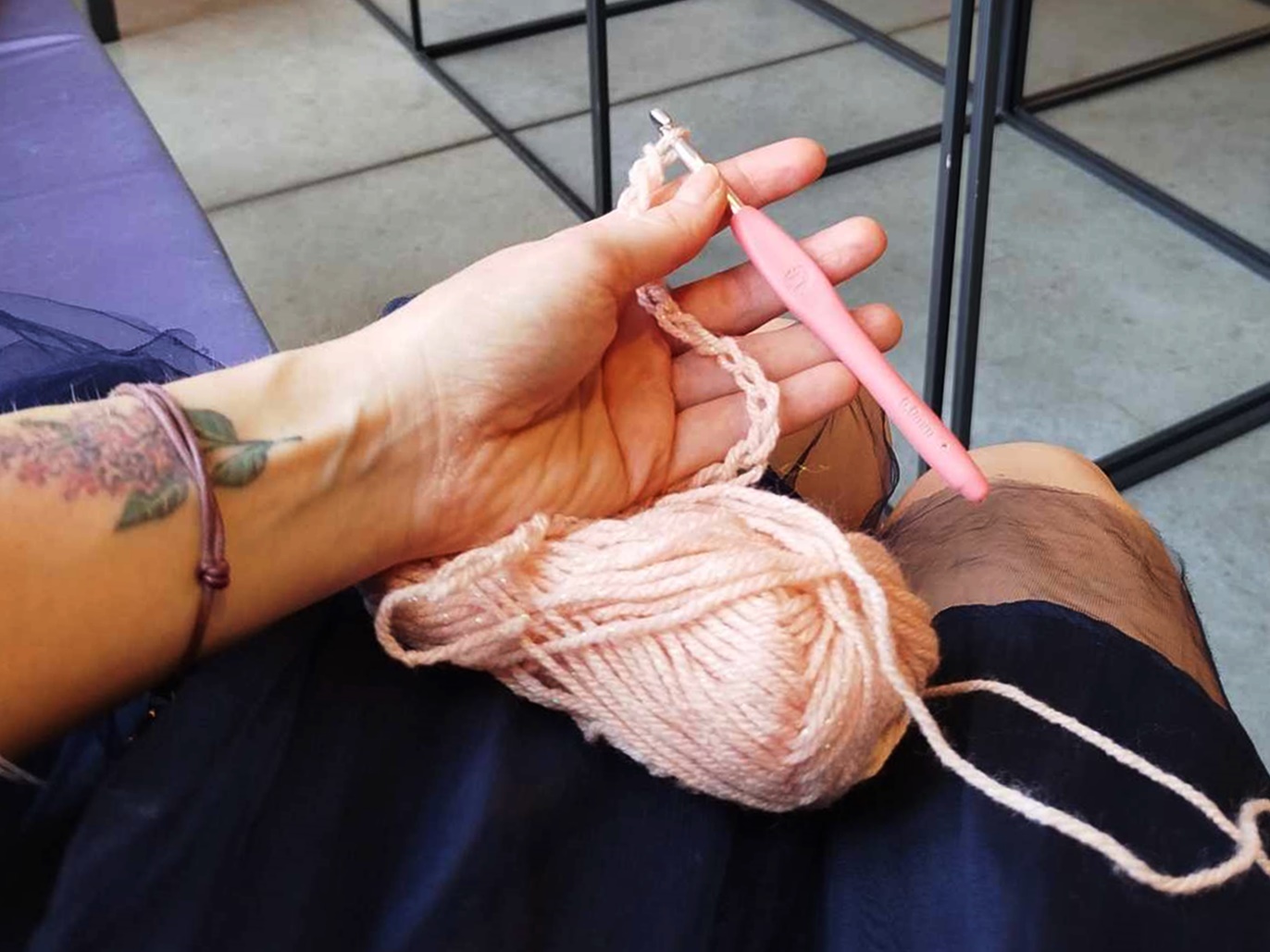 Kobieca ręka trzymająca szydełko i włóczkę.